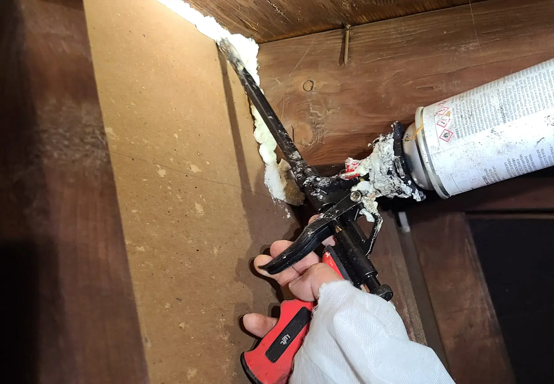 Sealant being applied to attic wall to block rodent entry points.