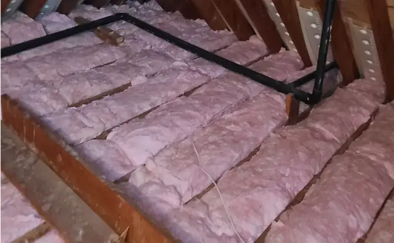 Insulation installation in attic for energy efficiency and temperature control.